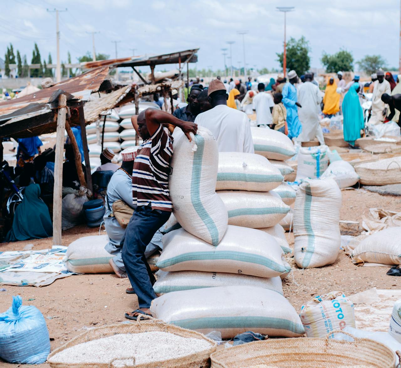 Bustling African market scene with people and large bags of grain, showcasing daily life.